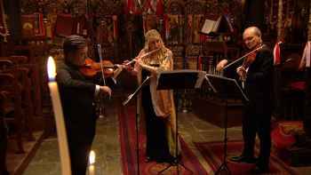 Three musicians playing their instruments and looking at their sheet music inside a church